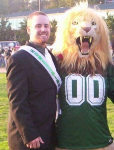 Brandon Berns standing beside Rocky II the Lion mascot at homecoming.