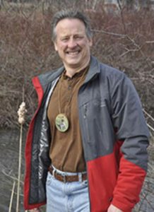 Fran Bires standing outdoors in wooded area.