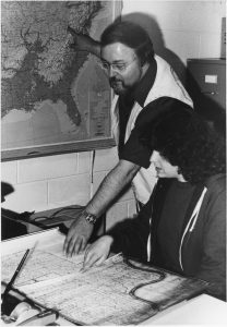 Don Kelly teaching a student, pointing at maps.