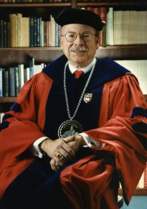 G. Warren Smith sitting down wearing graduation regalia.